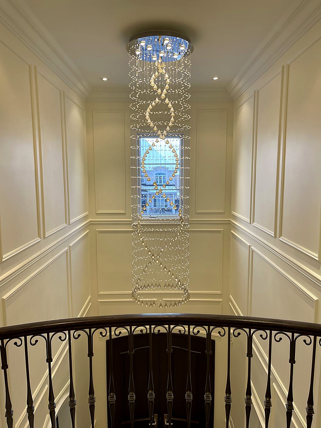Two-storey foyer with painted wainscoting and a cascading crystal chandelier