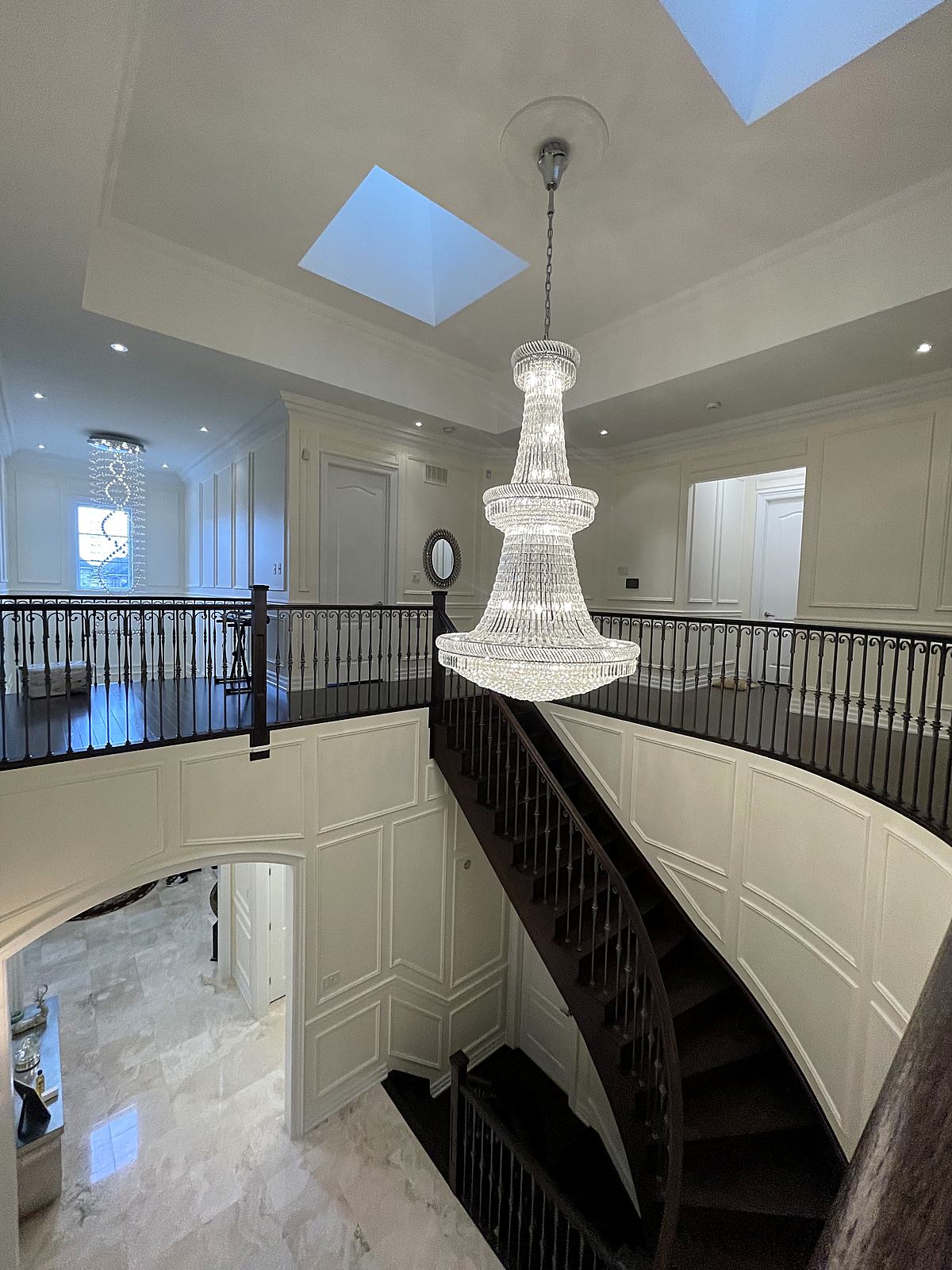 Grand curved staircase with full-height wall panelling and a crystal chandelier