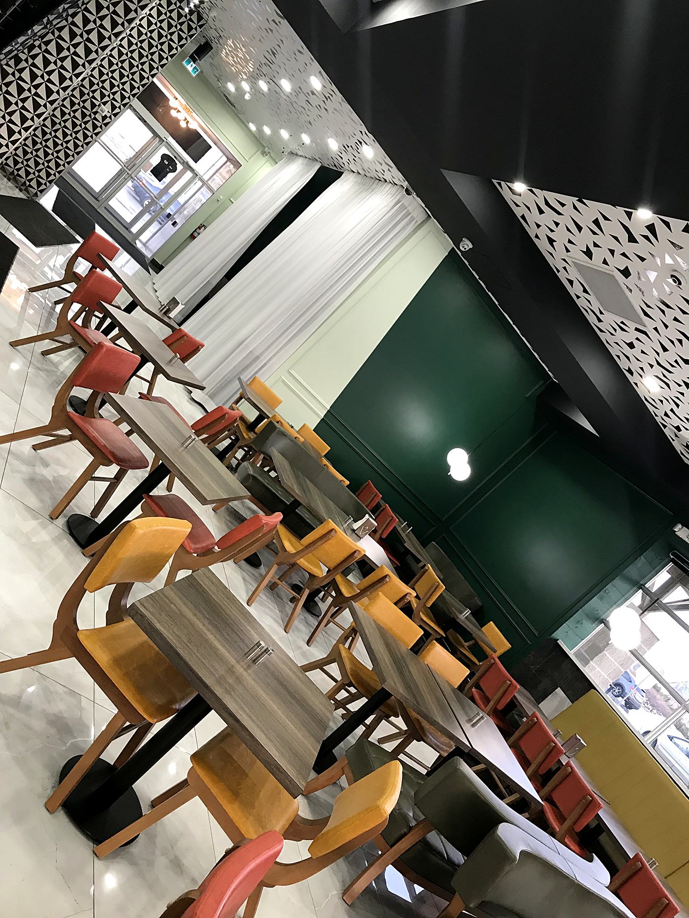 Restaurant dining room with green panelled feature wall and patterned ceiling wallpaper